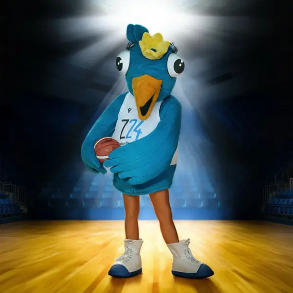 Ein blau-gelbes Maskottchen, Birdie, in Vogeloptik steht auf einem Basketballfeld unter Scheinwerferlicht. Es trägt ein Z24-Trikot, weiße Sportschuhe und hält einen Basketball in den Flügeln. Im Hintergrund sind die leeren Zuschauerränge einer Sporthalle zu sehen.