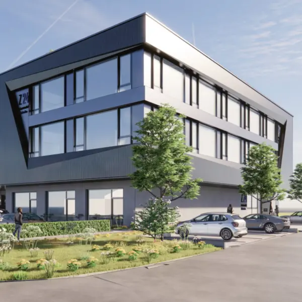 Modernes, dreigeschossiges Bürogebäude mit dunkelgrauer Fassade, großen Fensterfronten und weißen Akzenten. Vor dem Gebäude stehen Bäume, gepflegte Grünflächen sowie mehrere geparkte Autos.