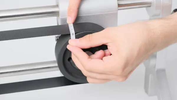 Messung der Riemenbreite an einem Antriebsriemen auf einer Riemenscheibe mithilfe eines Messstreifens, der von Hand am gespannten Riemen angelegt wird.