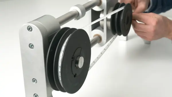 Messung des Abstands zwischen zwei Riemenscheiben mit einem Maßband an einer Maschinenkonstruktion.