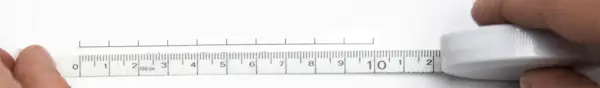 Nahaufnahme einer Hand mit Lineal, das eine gedruckte Maßstabsleiste auf einem Blatt Papier kontrolliert. Der Maßstab zeigt 10 cm Länge.