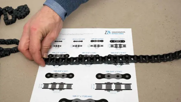 Hand legt eine Rollenkette auf eine Z24-Profilübersicht, um die exakte Teilung und Kettengröße zu vergleichen und zu bestimmen.