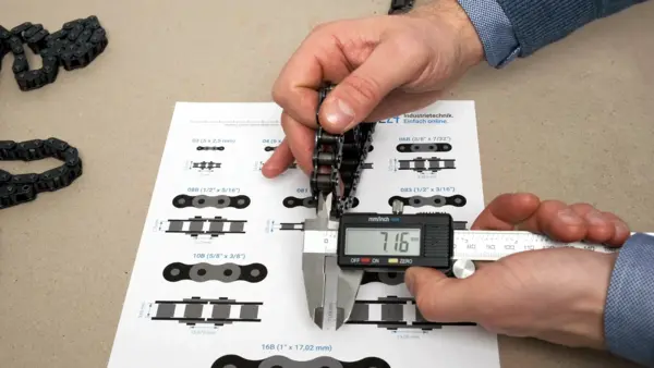 Hand misst mit einem digitalen Messschieber die innere Breite einer Rollenkette. Das Display zeigt 7,16 mm an.