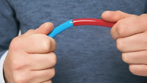 Zwei Hände verbinden einen blauen und einen roten PU-Rundriemen durch Zusammenfügen der Enden