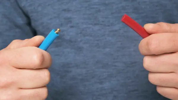 Zwei Hände halten die Enden eines blauen und eines roten PU-Rundriemens vor der Verbindung.