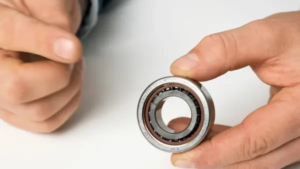 Hand hält ein Rillenkugellager aus Metall zur Ansicht.