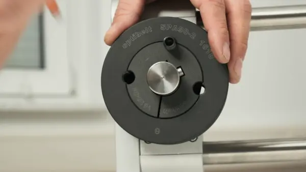 Eine Hand hält die montierte Keilriemenscheibe mit Taperbuchse, während eine Schraube zur Demontage in das Lösegewinde eingeschraubt wird.