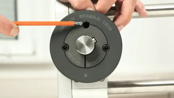 Eine Person führt einen Inbusschlüssel in das Lösegewinde einer montierten Taperbuchse an einer Keilriemenscheibe ein, um diese zu lösen.