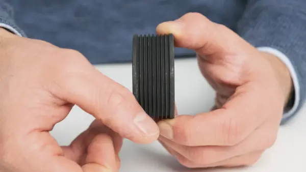 Nahaufnahme einer schwarzen Riemenscheibe mit Rillen, die von einer Person in den Händen gehalten wird.